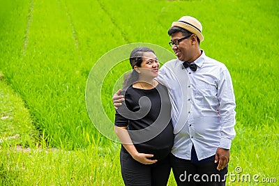 Pregnant woman and her husband smiling in nature Stock Photo