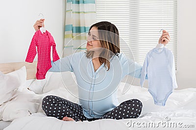 Pregnant Woman Holding Baby Clothes Stock Photo