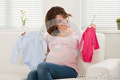 Pregnant Woman Holding Baby Clothes Stock Photo