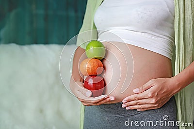 Pregnant woman holding Green-Red Apple and Orange fruit at her tummy. Dieting Concept Stock Photo