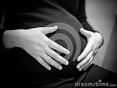 pregnant woman holding hands on her baby bump Stock Photo