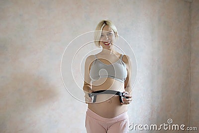 Pregnant woman holding headphone on belly on white background Stock Photo