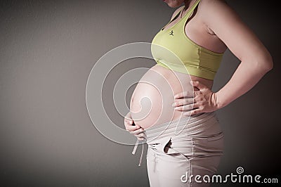 Pregnant woman is holding her stomach by her hand Stock Photo