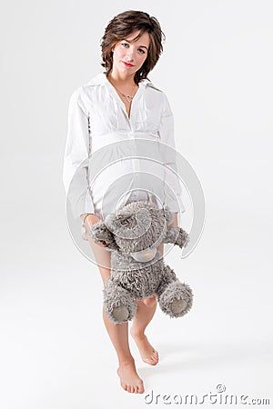 Pregnant woman holding soft toy. Pretty young woman carrying teddy bear. Stock Photo