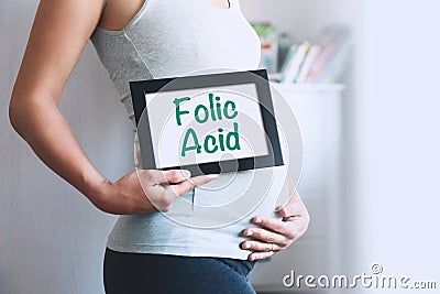 Pregnant woman holds whiteboard with text message - FOLIC ACID Stock Photo