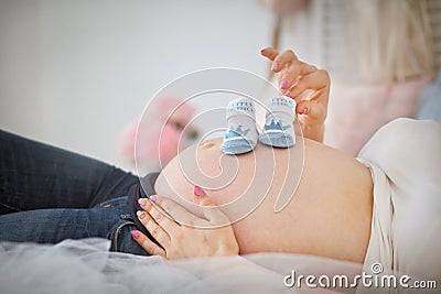 Pregnant woman holding blue baby booties Stock Photo