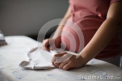 Pregnant woman at home preparing baby laundry Stock Photo