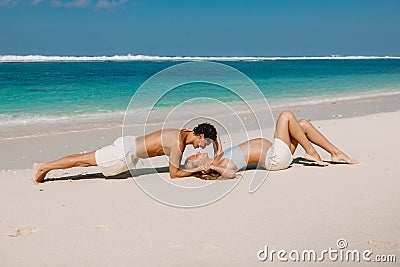 Pregnant woman with husband expecting baby kiss at tropical beach with blue sea Stock Photo