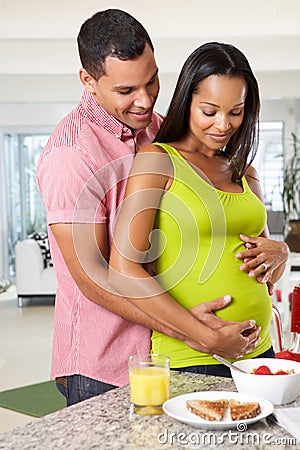 Pregnant Woman And Husband Having Breakfast In Kitchen Stock Photo