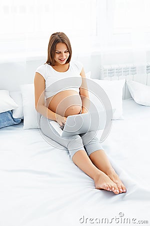 Pregnant woman with laptop. Beautiful pregnant woman working on Stock Photo