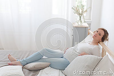 Pregnant woman lying on bed Stock Photo