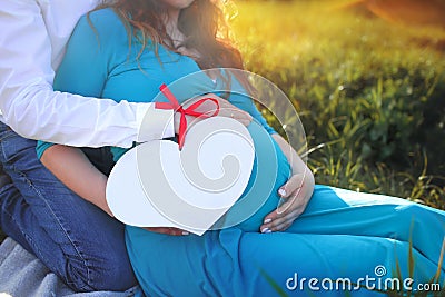 A pregnant woman and a man hold a paper heart with room for text. Copy space. Stock Photo