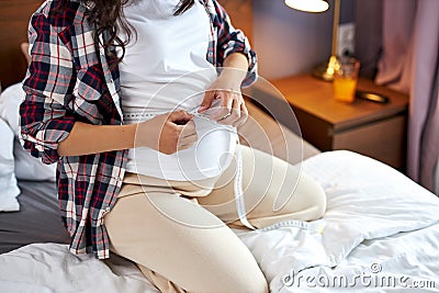 Pregnant woman measures her belly with a tape to keep track of her fetus development Stock Photo
