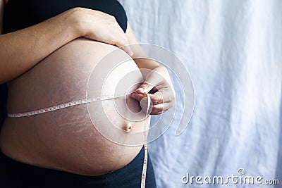 A pregnant woman measuring her belly with a tape Stock Photo