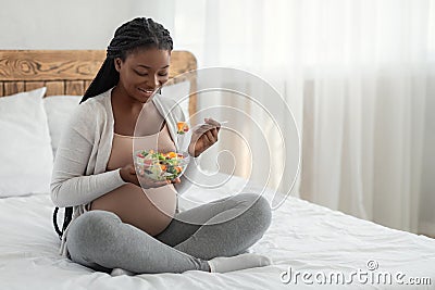 Pregnant Woman Nutrition. Happy Black Expecting Lady Eacting Vegetable Salad In Bed Stock Photo