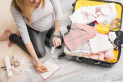 Pregnant woman packing for hospital and taking notes Stock Photo