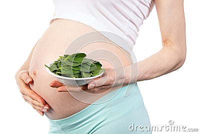 Pregnant woman with fresh green spinach, healthy nutrition containing iron during pregnancy Stock Photo