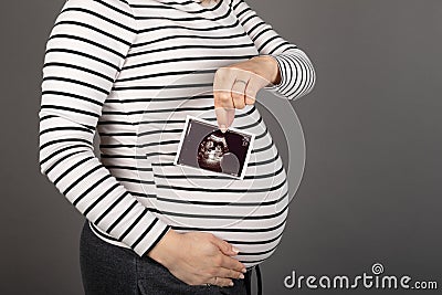 Pregnant woman posing on grey background Stock Photo