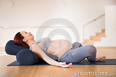 Pregnant woman is engaged in yoga. Reclined Bound Angle Pose or Supta Baddha Konasana Stock Photo