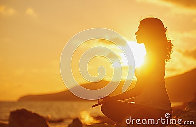 Pregnant woman practicing yoga in lotus position on beach at sun Stock Photo