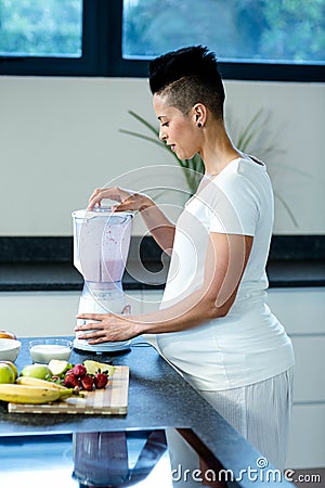 Pregnant woman preparing fruit juice in blender Stock Photo