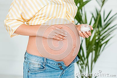 Pregnant woman putting sunscreen on her belly. Close up, isolated Stock Photo