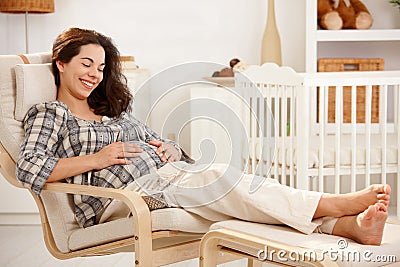 Pregnant woman resting in armchair in nursery Stock Photo