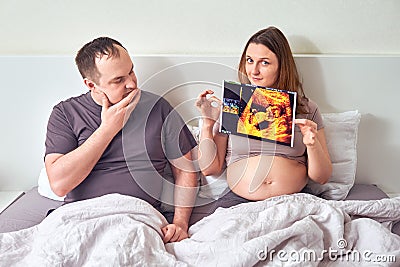 A pregnant woman shows a man an ultrasound with an unborn child. The husband looks incredulously at his wife pregnancy Stock Photo