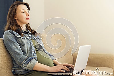 Pregnant woman sitting with laptop at home. Freelance working, p Stock Photo