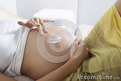 Pregnant Woman Smearing Lotion On Belly Stock Photo