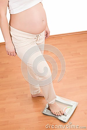 Pregnant woman standing on scales Stock Photo