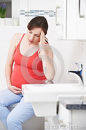 Pregnant Woman Suffering With Morning Sickness In Bathroom Stock Photo