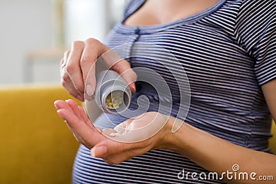 Close Up Of Pregnant Woman Taking Folic Acid Tablets Stock Photo