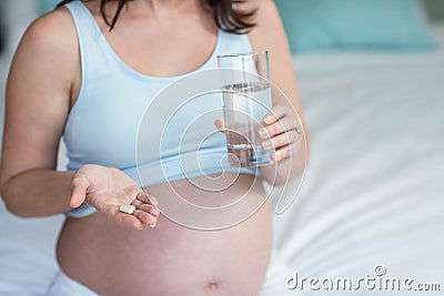 Pregnant woman taking a pill with water Stock Photo