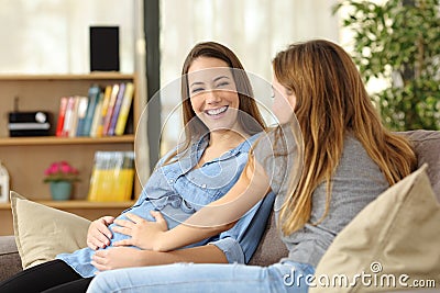 Pregnant woman talking with a friend who touches her belly Stock Photo