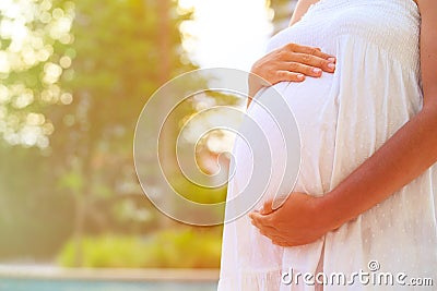 Pregnant woman touching her belly with love in nature Stock Photo