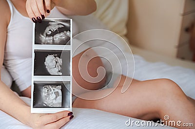 Pregnant woman with ultrasound picture of baby closeup. Snapshot of ultrasound and stomach. Pregnant on a pillow for pregnant wome Stock Photo