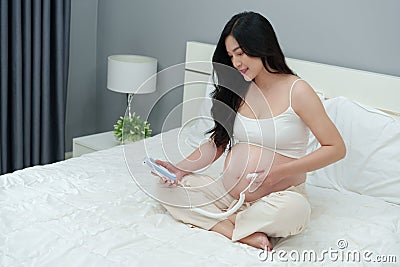 Pregnant woman using fetal droppler device to listening baby heartbeat Stock Photo
