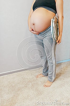 Pregnant woman with weights on gray background Stock Photo