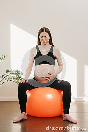 A pregnant woman is writhing in pain with her arm on her belly Stock Photo