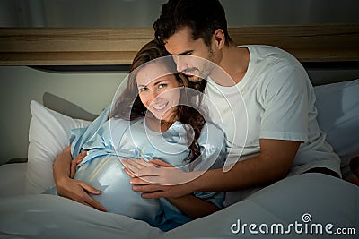 Pregnant woman with husband in bedroom with the atmosphere of having fun talking Stock Photo