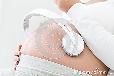 Pregnant women listening to music mozart effect good for the fetus by using headphones attached to the stomach, Stock Photo