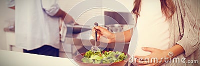 Pregnant woman mixing a salad in the kitchen Stock Photo