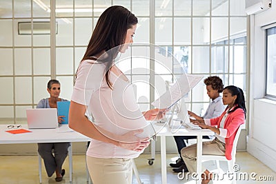 Pregnant worker touches belly and looks at file Stock Photo