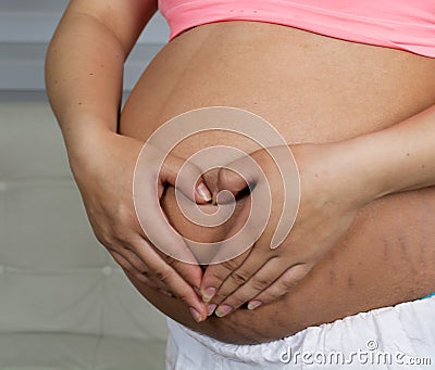 Pregnant wrap her arms around the belly Stock Photo