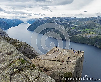 Preikestolen massive cliff at fjord Lysefjord, famous Norway viewpoint with group of tourists and hikers.Moody autumn Stock Photo