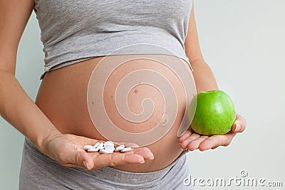Prenatal care. Pregnant woman with pills and apple. prenatal vitamins Stock Photo