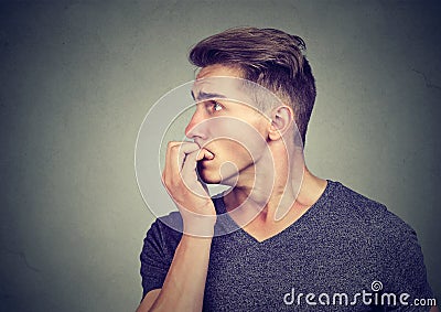 Preoccupied anxious young man biting his fingernails looking to the side Stock Photo