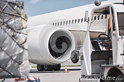 Loading of cargo containers against jet engine of plane Stock Photo