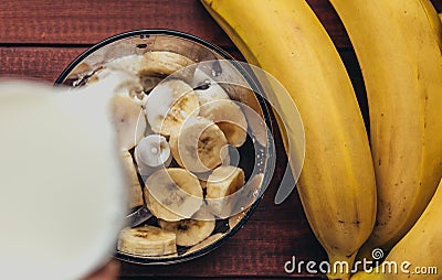 Preparation banana smoothie, pouring milk in a blender Stock Photo